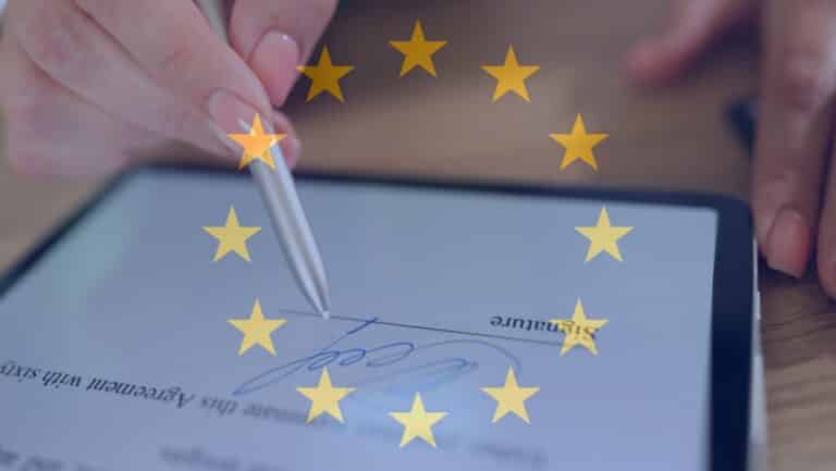 mains-de-femme-tenant-un-stylo-et-effectuant-une-signature-electronique-sur-tablette-avec-drapeau-europeen-en-fond
