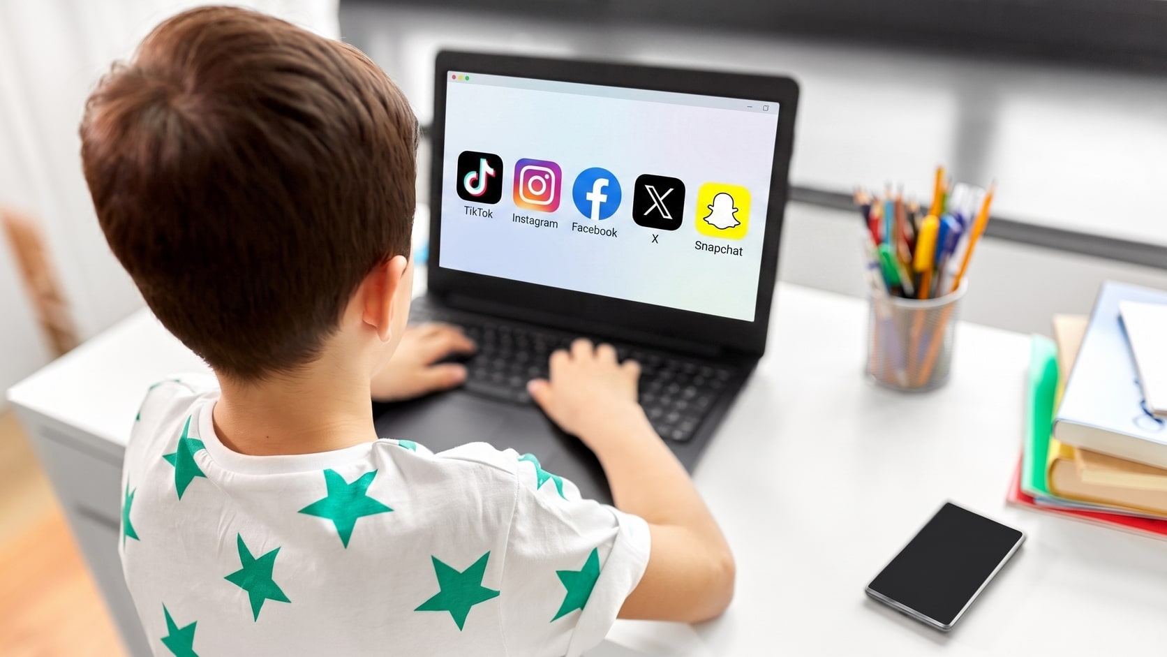 photographie-enfant-de-dos-sur-ordinateur-avec-logos-reseaux-sociaux